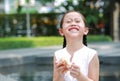 Happy Asian little girl eating bread with Stuffed Strawberry-filled dessert and Stained around her mouth in garden outdoor Royalty Free Stock Photo