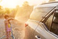 Happy asian little girl playing water from hose and spray to washing the car at outdoor in morning time Royalty Free Stock Photo