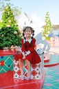 Happy Asian little girl in red dress sitting on big gift box against Christmas tree in a background Royalty Free Stock Photo