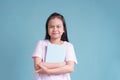 Happy Asian little girl standing holding the book on blue background isolated