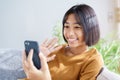 Happy Asian little girl video call on the smartphone and waving in greeting while sitting in the living room at home. Concept of