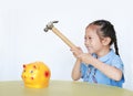 Happy Asian little kid girl in school uniform breaking piggy bank isolated on white background at table. Schoolgirl with Money Royalty Free Stock Photo