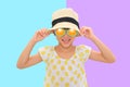 Happy Asian little kid girl wearing a sunglasses and straw hat isolated on cyan-purple background with clipping path. Summer and Royalty Free Stock Photo