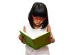 Happy Asian little preschool girl wearing red glasses holding and read a green book on white isolated background. Concept of Royalty Free Stock Photo