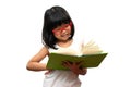 Happy Asian little preschool girl wearing red glasses holding and read a green book on white isolated background. Concept of Royalty Free Stock Photo