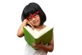 Happy Asian little preschool girl wearing red glasses holding and read a green book on white isolated background. Concept of Royalty Free Stock Photo