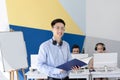 Happy Asian male helpdesk operator in headset holding documents at modern office Royalty Free Stock Photo