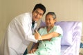 Happy Asian male patient lies on the bed, and raises her thumb up. When a doctor uses a stethoscope to listen to the lungs.