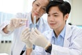 Happy Asian male scientist and senior female supervisor looking at the test tubes together Royalty Free Stock Photo