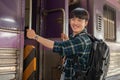 A happy Asian man backpacker is getting on the train, travel somewhere on his summer vacation Royalty Free Stock Photo