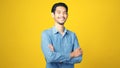 Happy asian man crossed arms while standing over isolated yellow background, Portrait of asia male smiling and looking at camera