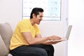 Happy asian man with laptop sitting on the couch Royalty Free Stock Photo