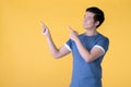 Happy Asian man pointing fingers up at empty copy space for text over yellow background Royalty Free Stock Photo