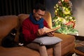 A happy Asian man is reading a book on a sofa while his cat is sitting beside him, Christmas at home Royalty Free Stock Photo