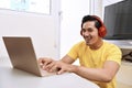 Happy asian man sitting with laptop and headphones Royalty Free Stock Photo