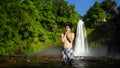 Happy asian man standing on cool water at waterfall from mountain. Adventure travel in holiday freedom concept Royalty Free Stock Photo