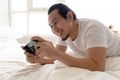 Happy man stays home and play mobile game in his apartment.