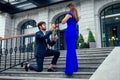 Happy asian man in stylish black suit falling knee in front of his beautiful woman in blue long dress asking proposal Royalty Free Stock Photo