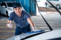 Happy asian man in uniform holds the microfiber in hand and polishes the car, Car wash service concept Royalty Free Stock Photo