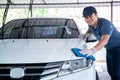 Happy asian man in uniform holds the microfiber in hand and polishes the car, Car wash service concept Royalty Free Stock Photo