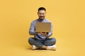 Happy Asian Man Using Laptop While Sitting On Floor Over Yellow Background Royalty Free Stock Photo