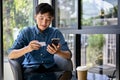 Happy Asian man using mobile banking application to pay his bills online Royalty Free Stock Photo