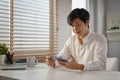 Happy Asian man using mobile banking application to transfer money or pay online bills Royalty Free Stock Photo