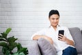 Happy Asian man using smartphone in living room Royalty Free Stock Photo