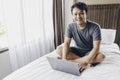 Happy Asian man is working with his laptop on his bed. Concept of freelancer successful lifestyle Royalty Free Stock Photo