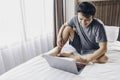 Happy Asian man is working with his laptop on his bed. Concept of freelancer successful lifestyle Royalty Free Stock Photo