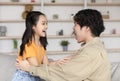 Happy asian millennial man and teen daughter look at each other with open mouths, have fun