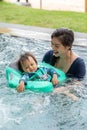 Happy Asian mom and baby playing in swimming pool using swim ring for leaning to swim relax in holiday. Vacation of family mother Royalty Free Stock Photo