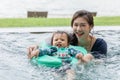 Happy Asian mom and baby playing in swimming pool using swim ring for leaning to swim relax in holiday. Vacation of family mother Royalty Free Stock Photo