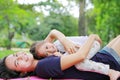 Happy Asian mom embrace her daughter lying in the green garden with looking camera. Funny mother and child girl playing in summer Royalty Free Stock Photo