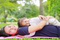 Happy Asian mom embrace her daughter lying in the green garden with looking camera. Royalty Free Stock Photo