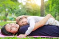Happy Asian mom embrace her daughter lying in the green garden with looking camera Royalty Free Stock Photo