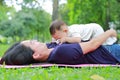 Happy Asian mom embrace her son lying in the green garden. Funny mother and infant baby boy playing in summer park Royalty Free Stock Photo