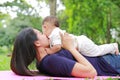 Happy Asian mom embrace her son lying in the green garden. Funny mother and infant baby boy playing in summer park Royalty Free Stock Photo