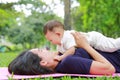 Happy Asian mom embrace her son lying in the green garden. Funny mother and infant baby boy playing in summer park