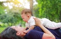Happy Asian mom embrace her son lying in the green garden. Funny mother and infant baby boy playing in summer park Royalty Free Stock Photo