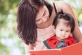 Happy asian mother and cute little baby girl reading a book Royalty Free Stock Photo