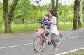 Happy asian mother and daughter arm stretch and riding bicycle together in park Royalty Free Stock Photo