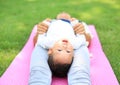 Happy Asian mother playing with her son and lying on green lawn at park Royalty Free Stock Photo