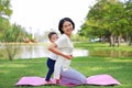 Happy Asian mother playing with her son and lying on green lawn at park Royalty Free Stock Photo