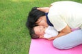 Happy Asian mother playing with her son and lying on green lawn at park Royalty Free Stock Photo
