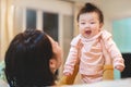 Happy Asian mother plays with baby holding girl in hands, baby smile, Living lifestyle family indoors concept Royalty Free Stock Photo