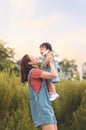 Happy Asian mother plays with daughter and holding girl in hands at park with nice sky, Baby smile and laughing, Family concept Royalty Free Stock Photo