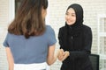 Happy asian muslim businesswoman sales manager shake hand of asian lady client make deal with female customer at meeting with lapt