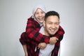 Happy Asian muslim couple posing to camera, man carry his wife on his back, piggyback, smiling cheerful expression Royalty Free Stock Photo