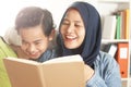 Happy Asian muslim mother wearing hijab reading book together with her little boy, mom and kid learning together, happy single Royalty Free Stock Photo